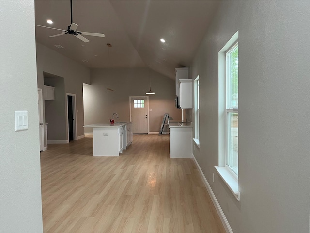 kitchen featuring an island with sink, ceiling fan, light countertops, white cabinets, and a sink
