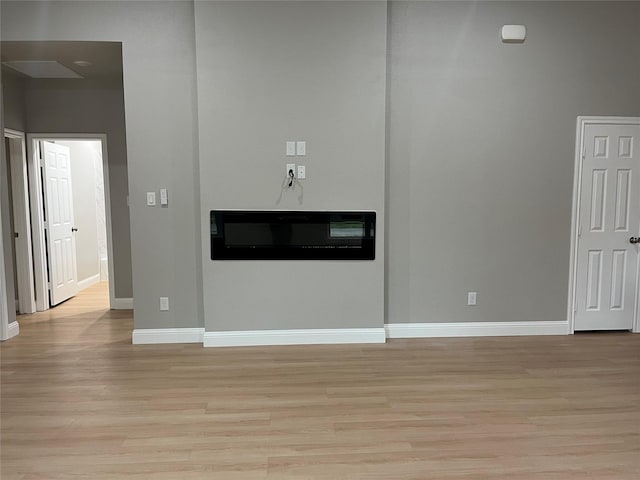 unfurnished living room featuring baseboards and light wood-type flooring