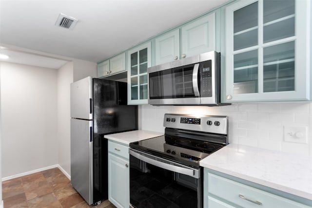 4211 Fairway Dr, Granbury, TX 76049 - kitchen featuring stainless steel appliances, backsplash, baseboards, glass insert cabinets, and light stone finish flooring