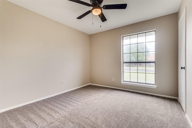 carpeted spare room featuring baseboards and a ceiling fan