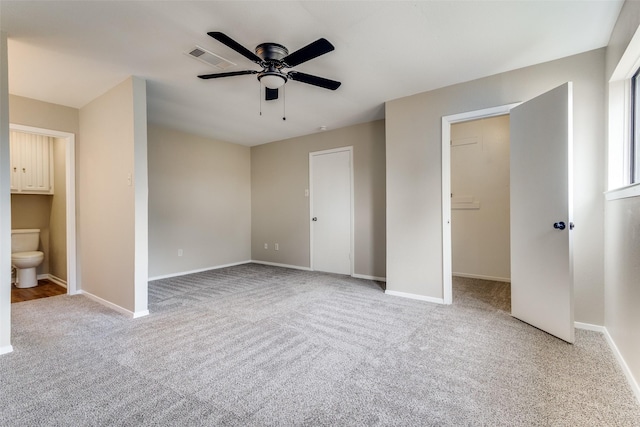 unfurnished bedroom with a walk in closet, baseboards, carpet, and visible vents