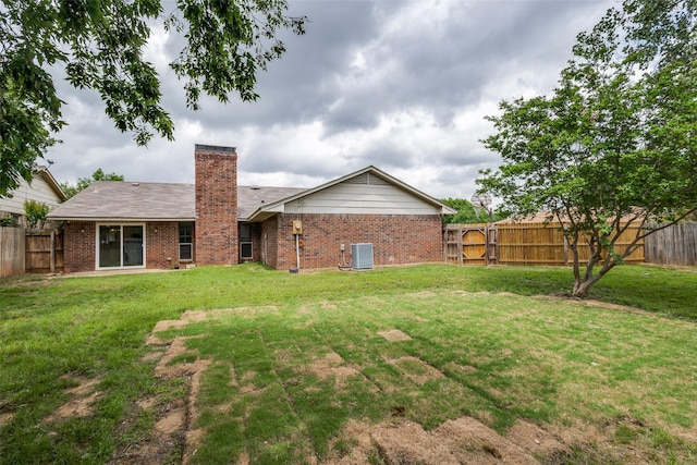 back of property featuring central air condition unit, a lawn, a fenced backyard, and brick siding