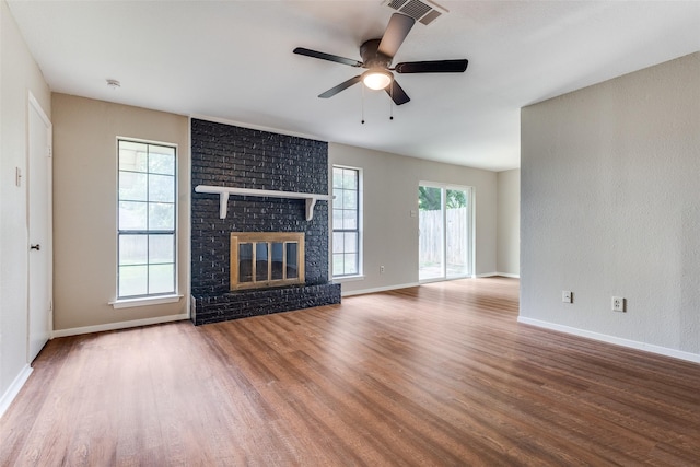 unfurnished living room featuring ceiling fan, a fireplace, baseboards, wood finished floors, and visible vents