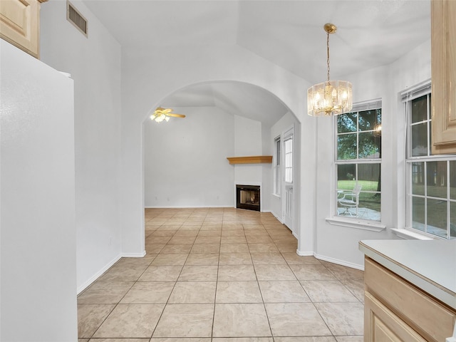unfurnished living room with visible vents, arched walkways, a fireplace, light tile patterned floors, and ceiling fan with notable chandelier