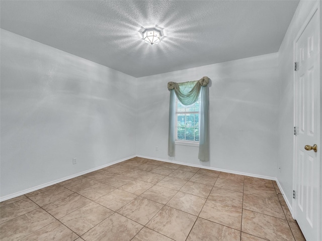 spare room featuring baseboards and a textured ceiling