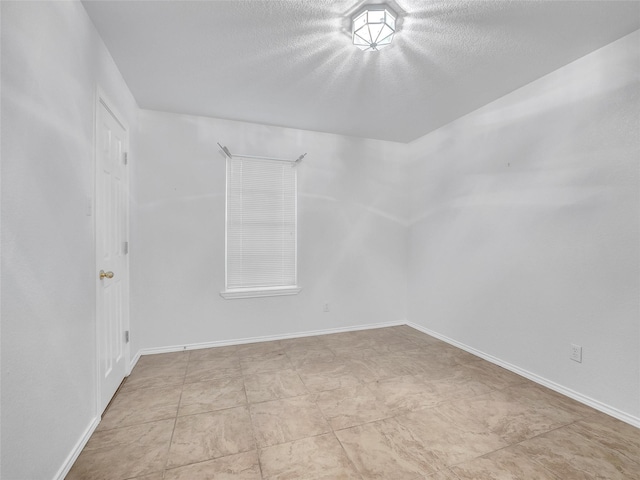 unfurnished room with a textured ceiling and baseboards