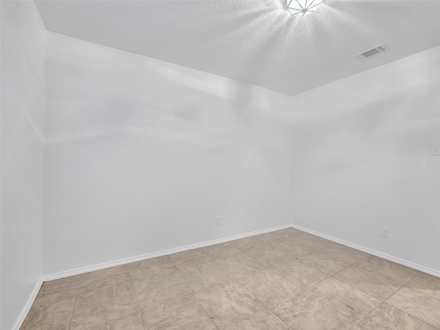 unfurnished room featuring a textured ceiling, baseboards, and light floors