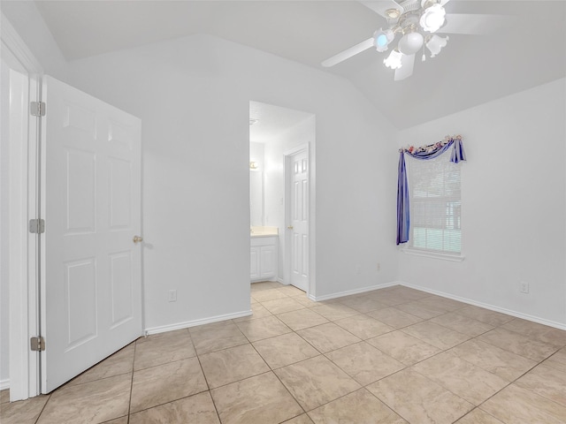 unfurnished bedroom with connected bathroom, a ceiling fan, baseboards, light tile patterned floors, and vaulted ceiling