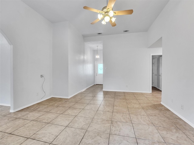 empty room featuring visible vents, arched walkways, baseboards, and ceiling fan