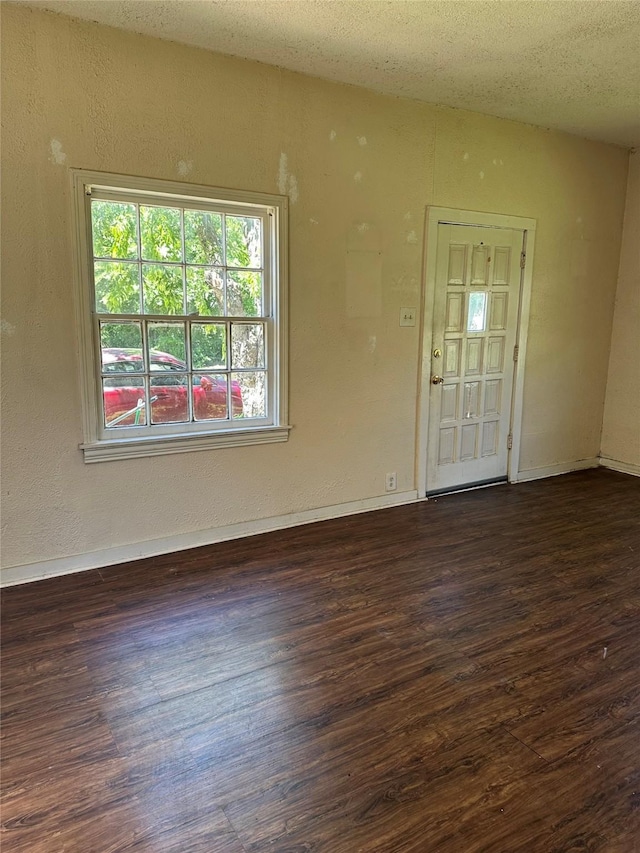 unfurnished room featuring baseboards, dark wood-style floors, and a textured ceiling