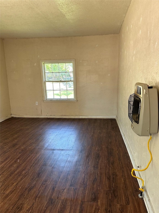unfurnished living room featuring heating unit, a textured ceiling, and wood finished floors