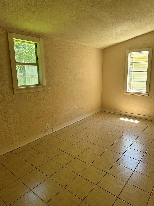 unfurnished room featuring a textured ceiling, a textured wall, and light tile patterned flooring