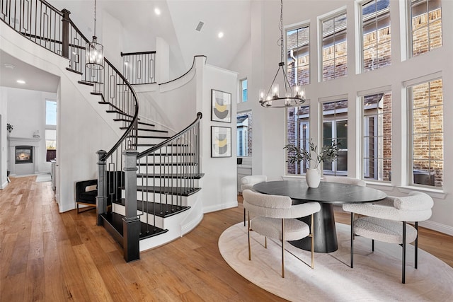 dining space featuring stairway, wood-type flooring, a chandelier, and a towering ceiling