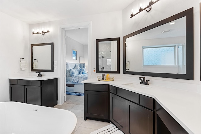 full bath with a sink, a freestanding bath, ensuite bath, and two vanities