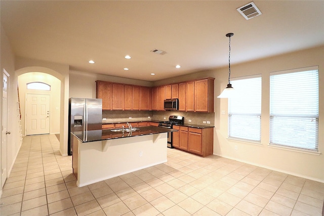 kitchen with dark countertops, appliances with stainless steel finishes, a sink, backsplash, and visible vents