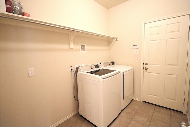 clothes washing area with laundry area, baseboards, light tile patterned floors, and washing machine and dryer