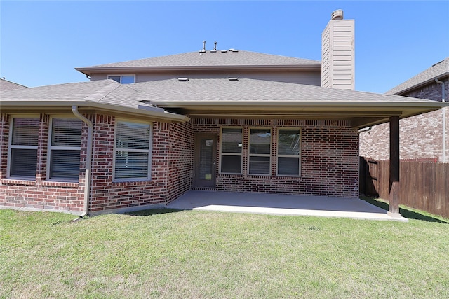 rear view of property featuring fence, a lawn, a patio area, and brick siding
