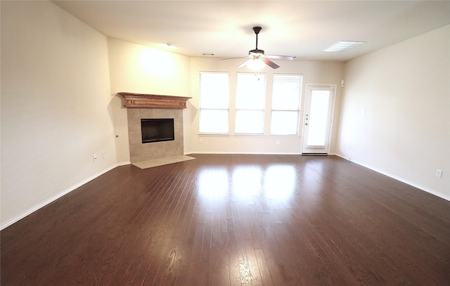 unfurnished living room with dark wood-style flooring, a ceiling fan, baseboards, and a tile fireplace