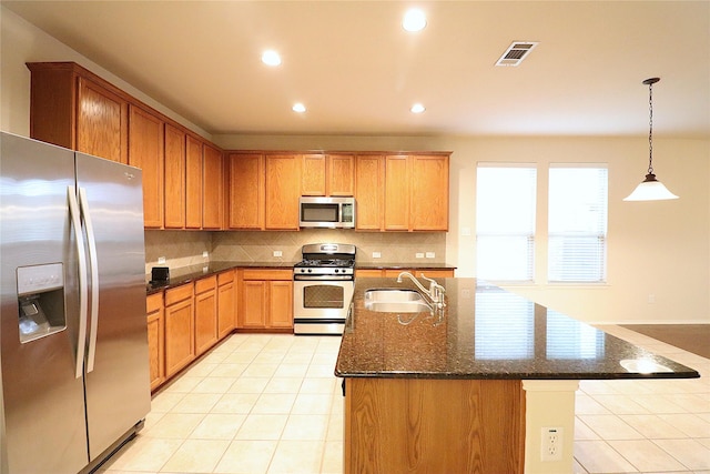kitchen with appliances with stainless steel finishes, a sink, light tile patterned floors, backsplash, and visible vents