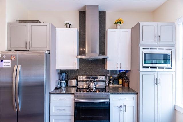 kitchen with appliances with stainless steel finishes, white cabinets, backsplash, and wall chimney exhaust hood