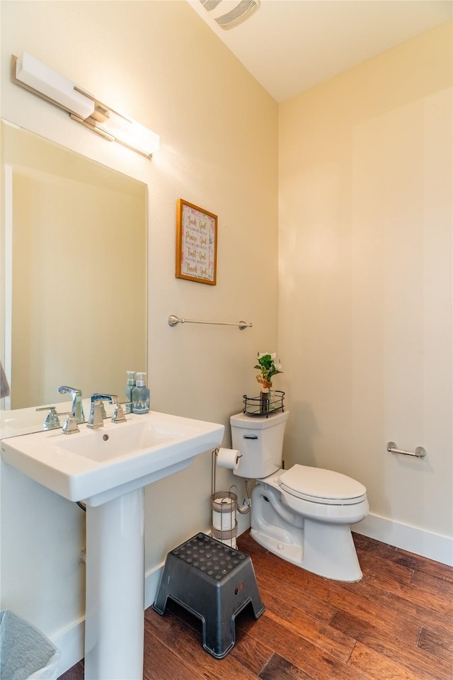 bathroom featuring baseboards, a sink, wood finished floors, and toilet