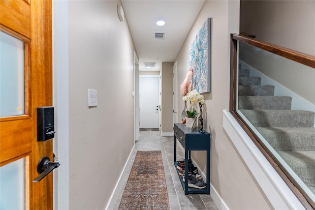 hallway featuring baseboards, visible vents, and stairway