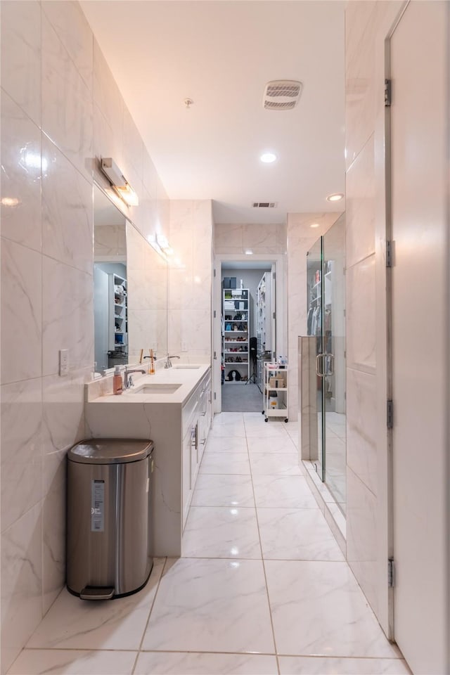 full bathroom featuring visible vents, marble finish floor, a spacious closet, and tile walls