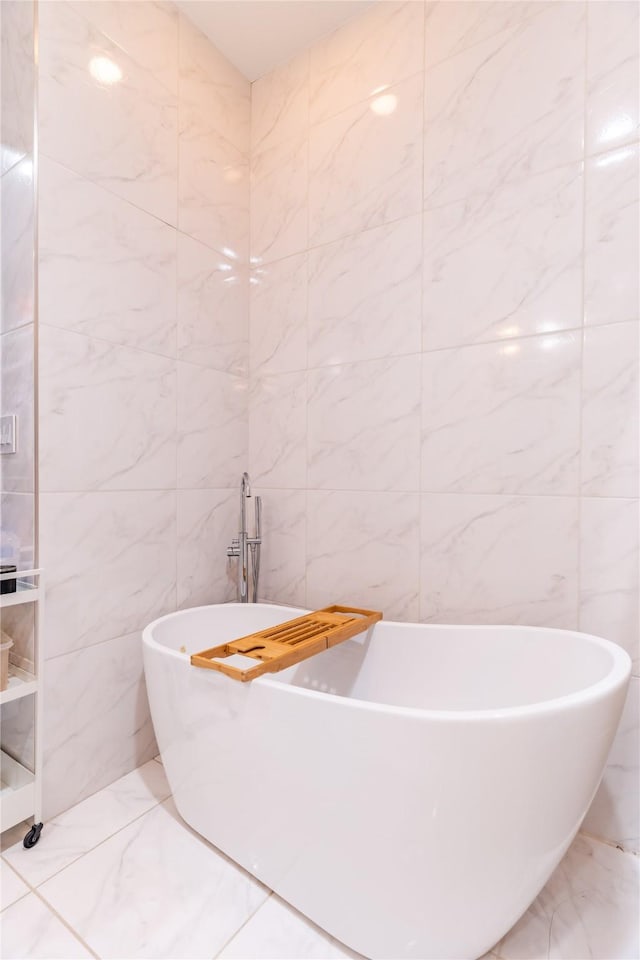 full bath with tile walls, a soaking tub, and marble finish floor