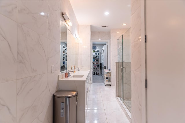 bathroom featuring a walk in closet, visible vents, tile walls, a stall shower, and a sink