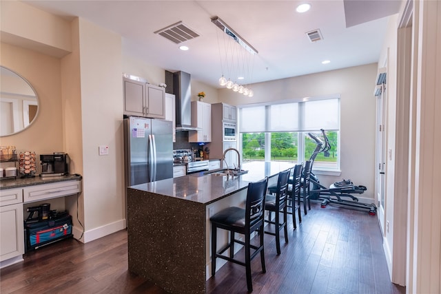 kitchen with visible vents, a sink, wall chimney range hood, and stainless steel appliances