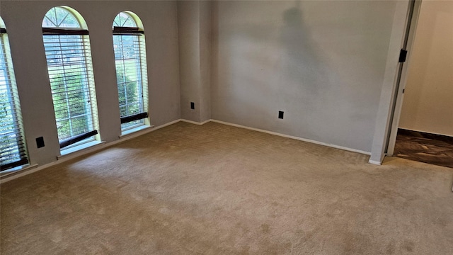 carpeted spare room featuring baseboards