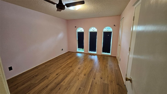 empty room featuring baseboards, a ceiling fan, a textured ceiling, and wood finished floors