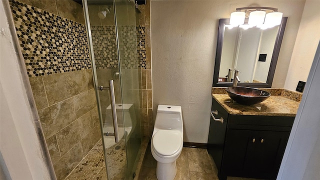 full bathroom featuring vanity, a textured wall, toilet, baseboards, and a shower stall