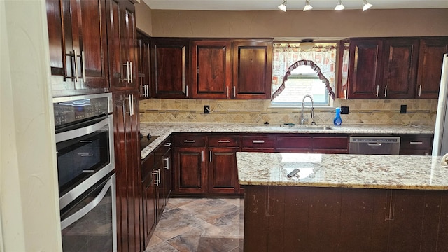 kitchen featuring a sink, appliances with stainless steel finishes, tasteful backsplash, and light stone countertops