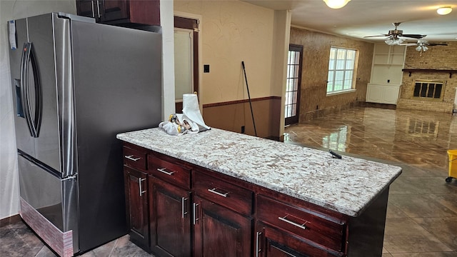 kitchen featuring a ceiling fan, stainless steel refrigerator with ice dispenser, open floor plan, and reddish brown cabinets