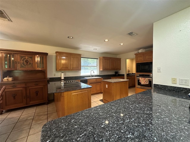 824 Imogene Ct, Azle, TX 76020 - kitchen with black microwave, stainless steel oven, a center island, a sink, and light tile patterned floors
