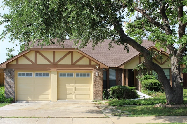 view of front of home featuring a garage, a shingled roof, driveway, and brick siding