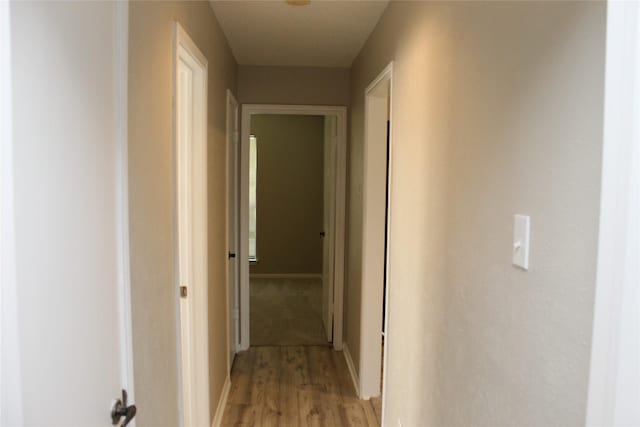 corridor featuring baseboards and light wood finished floors
