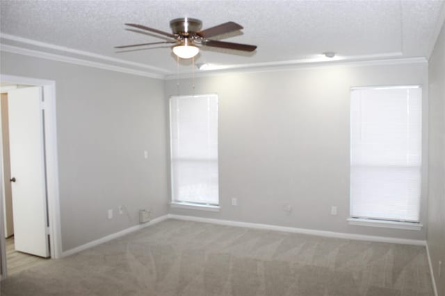 carpeted empty room with a ceiling fan, baseboards, ornamental molding, and a textured ceiling
