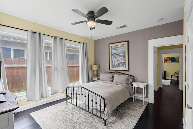 bedroom with visible vents, a ceiling fan, baseboards, and dark wood-style flooring