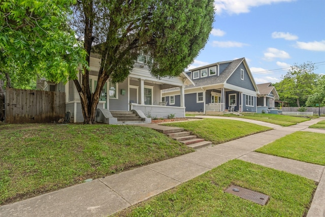 view of front of house with fence, a porch, and a front lawn
