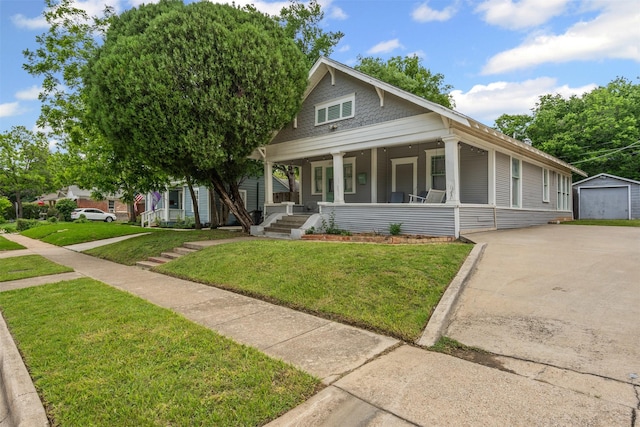view of front of property with an outbuilding, covered porch, concrete driveway, and a front lawn