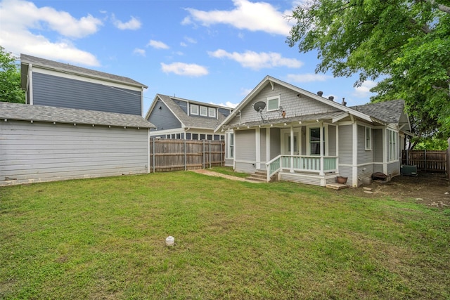 rear view of property featuring a fenced backyard and a lawn