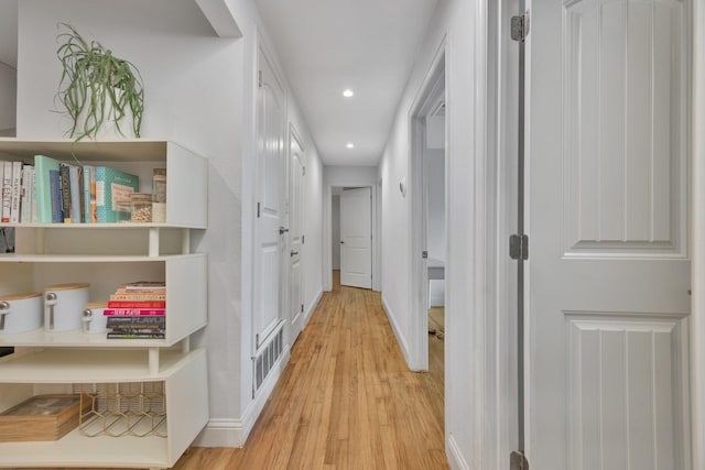 hallway featuring light wood-style flooring, baseboards, and recessed lighting