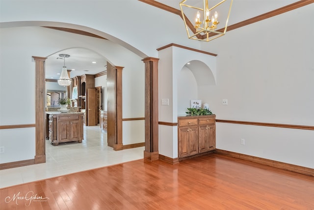 spare room featuring an inviting chandelier, baseboards, and light wood finished floors