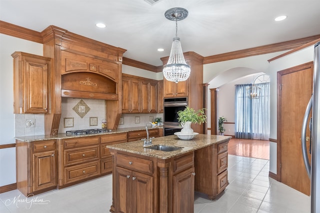 kitchen featuring brown cabinets, stainless steel appliances, arched walkways, and a sink
