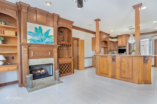 kitchen featuring oven, baseboards, decorative columns, and brown cabinetry