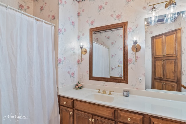 full bath with wallpapered walls and vanity