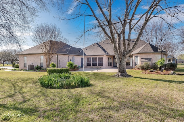 back of house with a shingled roof, central AC, brick siding, a patio area, and a yard