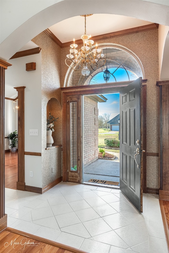 entrance foyer featuring an inviting chandelier, ornamental molding, arched walkways, and light tile patterned floors